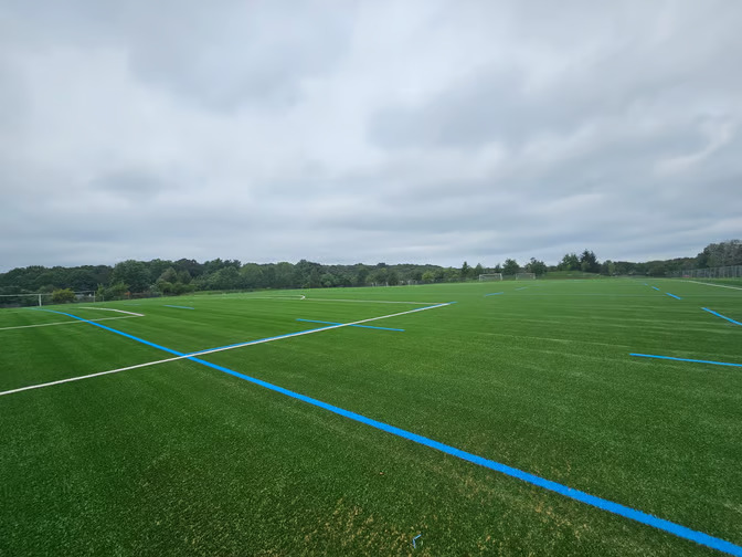 Blue and white lines painted on a turf field at Skyline Park in Brookline.